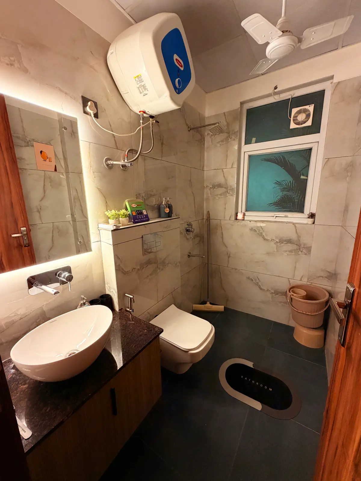 Modern bathroom with vessel sink, backlit mirror and marble-look tiles