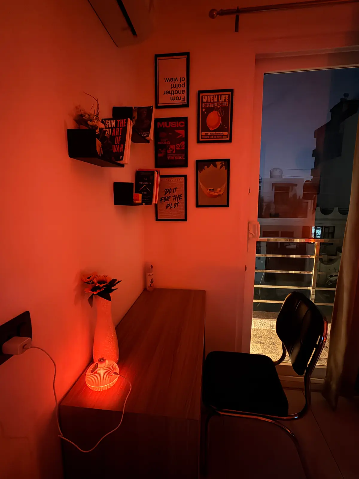 Work desk by the balcony with sunflowers, books and framed prints